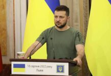 Man at a podium with Ukrainian flags