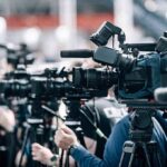 Emergency Declared: Homes Red-Tagged Broadcast cameras on tripods at a press event