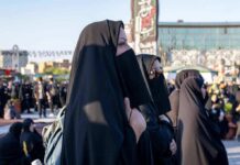 Women in black veils standing among a crowd outdoors
