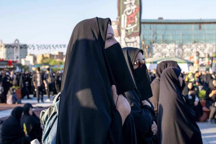 Women in black veils standing among a crowd outdoors
