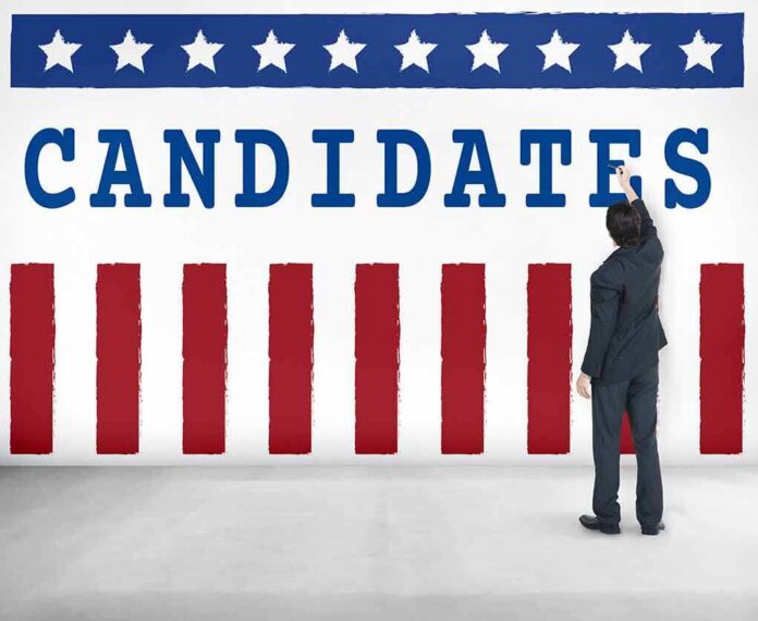 shutterstock_470723279 Man in suit writing on wall with word candidates and patriotic design