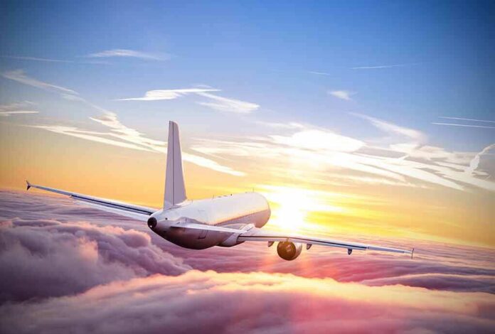 shutterstock_553131187 Airplane flying above clouds at sunrise