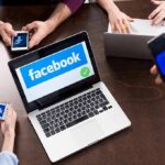 Meta’s Gamble: Crowds Judge Truth Now Laptop with Facebook on screen surrounded by smartphones