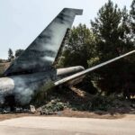 Wrecked airplane tail section beside a road