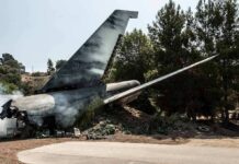 Wrecked airplane tail section beside a road