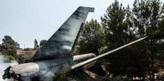 Wrecked airplane tail section beside a road
