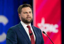 Crackdown Hits Outsourcing Giants Man in suit speaking at a podium with microphone