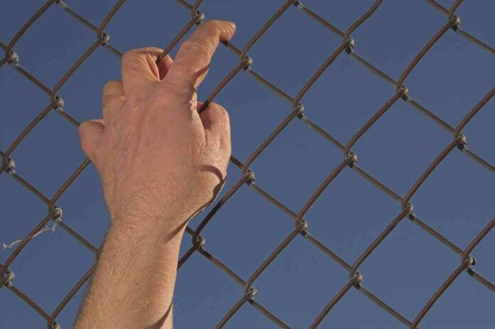 shutterstock_10213060 Hand gripping a chain-link fence