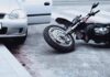 Motorcycle lying on the street beside a car with an open door