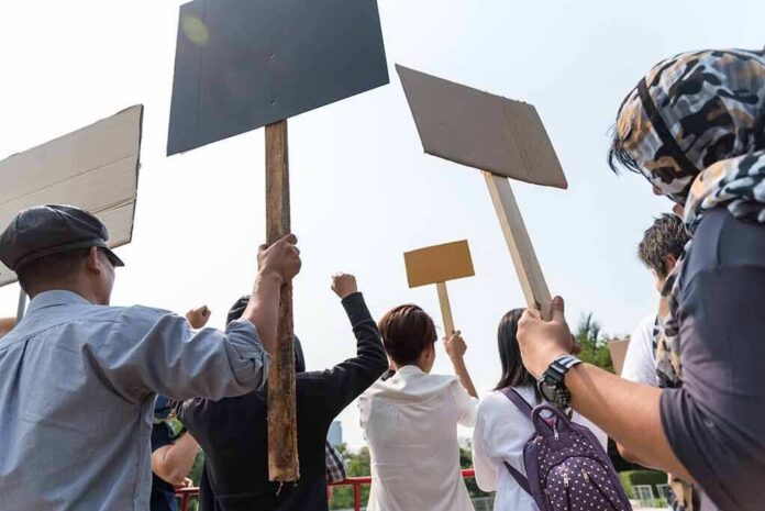 shutterstock_1051291337 Group of people holding protest signs outdoors