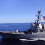 An Unusual Naval Encounter Ends in Flames Naval destroyer sailing on open sea with flag flying
