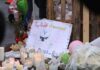 Vigil Flames, Unsettling Questions Linger A memorial site with candles, flowers, and a hand-drawn poster