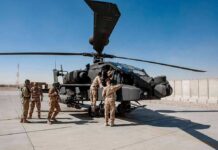 Deaths, Injuries, and Flames Trigger a Major Investigation Soldiers inspect a military attack helicopter on a tarmac