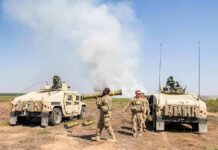 Soldiers with two military vehicles during field exercise