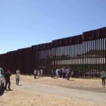 Border Flip: Deportation Reunites Families Border fence with group of people and a patrol vehicle