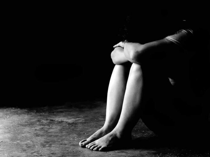 Person sitting on floor with knees hugged in low light