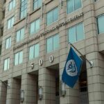 U.S. government building facade with American and blue departmental flags