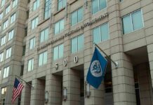 U.S. government building facade with American and blue departmental flags