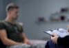 Therapist taking notes while man sits on couch
