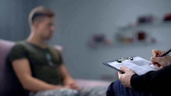 Therapist taking notes while man sits on couch