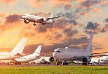Passenger jets on airport tarmac with one aircraft landing at sunset