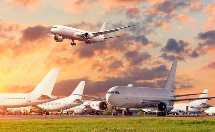 Passenger jets on airport tarmac with one aircraft landing at sunset