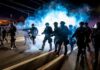 Tens Of Thousands Deploy – Paris On Edge Riot police advance through tear gas at night on a city street