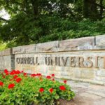 Cornell University stone entrance sign with red flowers
