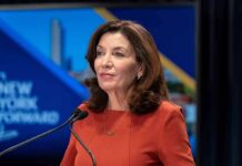 Kathy Hochul speaking at a podium with microphones