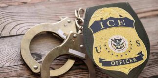 ICE officer badge and handcuffs on wooden surface
