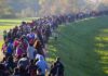 Large crowd of people walking along a grassy embankment