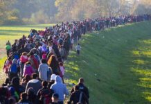 Large crowd of people walking along a grassy embankment