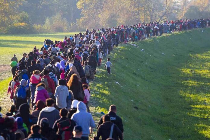 Large crowd of people walking along a grassy embankment